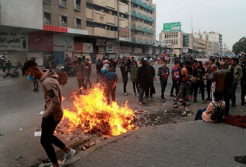 Anti-government protesters set a fire while security forces use tear gas during clashes in central Baghdad. AP Photo