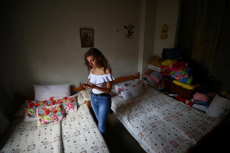 Tatiana Hasrouty uses her mobile phone next to the bed of her father Ghassan Hasrouty, a missing silo employee. Reuters