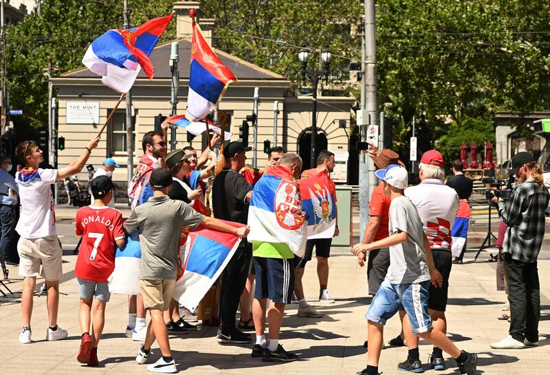 Supporters of tennis player Novak Djokovic wave national flags as they gather in front of Federal Court building in Melbourne. AFP