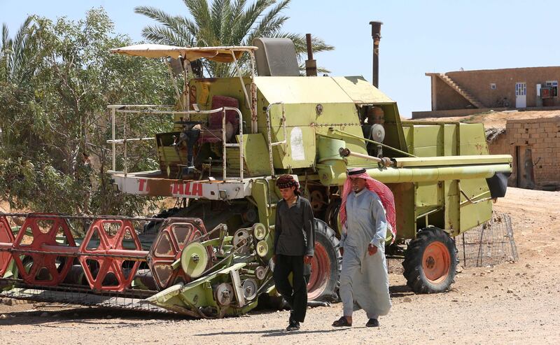 Abu Majid and a relative walk past a farm vehicle.
