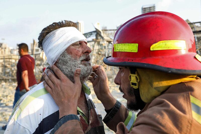A wounded man is checked by a fireman near the scene of the explosion in Beirut. AFP