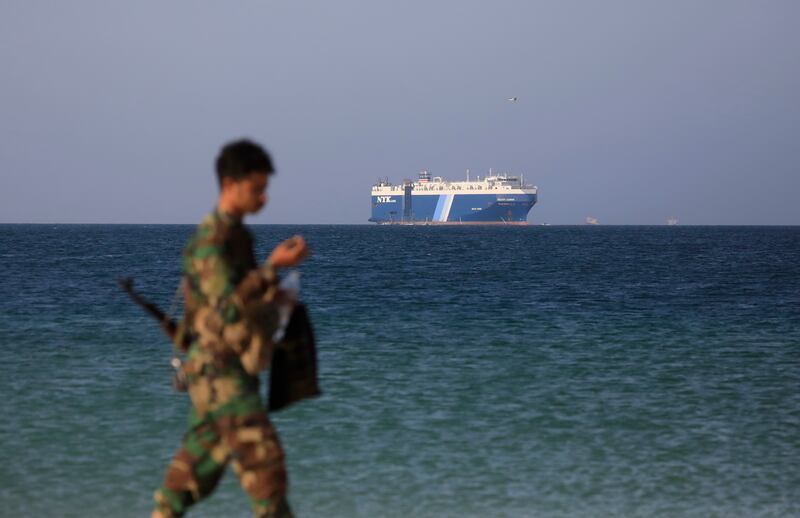 A Houthi fighter walks on the beach with the Galaxy Leader cargo ship, seized by the Yemeni rebel group in the Red Sea last month, in the background. EPA