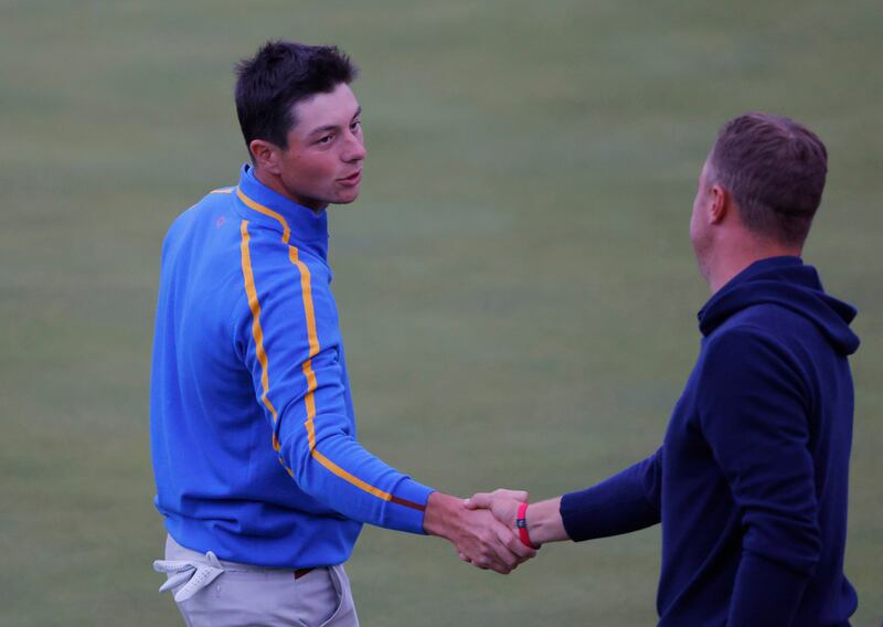 Team USA's Justin Thomas shakes hands with Team Europe's Viktor Hovland on the 18th green after halving the match during the Four-balls. Reuters