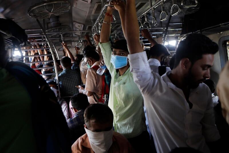 Indian commuters, some wearing protective masks as a precaution against Covid-19, travel in a crowded local train in Mumbai, India. AP Photo
