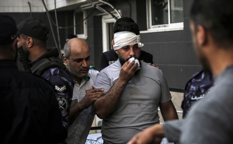 An injured Palestinian man is led towards a hospital following the strikes. AFP