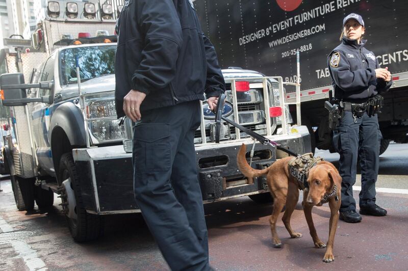 Emergency service personnel with a bomb sniffing dog work outside the building that houses New York Governor Andrew Cuomo's office after a report of a suspicious package, Wednesday, Oct. 24, 2018, in New York. The U.S. Secret Service said Wednesday that it intercepted a bomb that was addressed to former Secretary of State Hillary Clinton and also discovered a possible explosive sent to former President Barack Obama.  (AP Photo/Mary Altaffer)