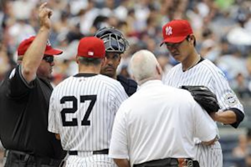 Wang Chien-Ming, right, rests his glove on the shoulder of the trainer Steve Donahue as umpire Wally Bell signals the bullpen for a new pitcher.