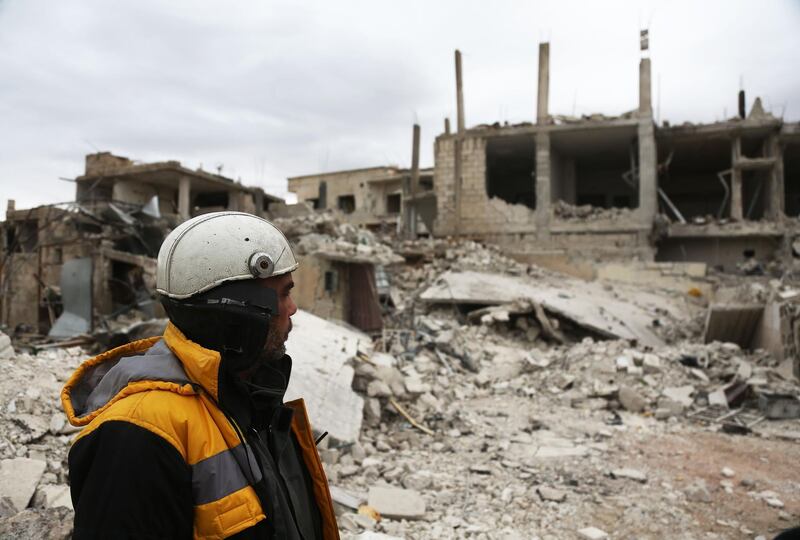 Forty-five-year-old Samir Salim (L), who along with his three brothers are members of the White Helmets rescue forces, looks out at destroyed buildings in the town of Medeira in Syria's rebel-held Eastern Ghouta area on February 12, 2018. 

For years, Samir Salim and his brothers rescued neighbours and relatives pinned underground after bombardment on Syria's rebel-held Eastern Ghouta. But last week, they could not save their own mother. / AFP PHOTO / ABDULMONAM EASSA