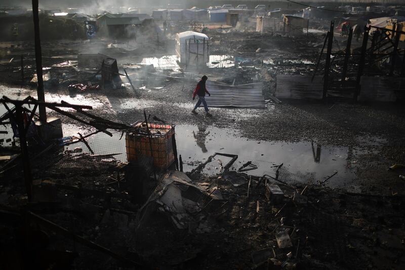 A migrant walks through the burnt out Jungle camp as authorities demolish the site on October 26, 2016. Getty Images