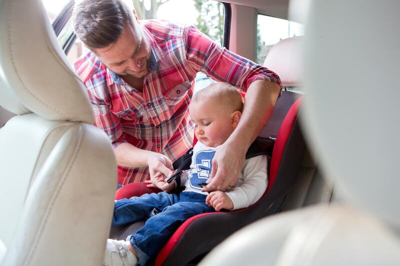 Shot of a father putting his son in a car seat, he is leaning over fastening the belt. (Getty Images) *** Local Caption ***  na01de-letters-seatbelt.jpg