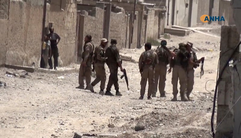 This frame grab from video released Thursday, July 6, 2017 and provided by Hawar News Agency, a Syrian Kurdish activist-run media group, shows Syrian citizens looks to U.S.-backed Syrian Democratic Forces (SDF) fighters in the eastern side of Raqqa, Syria. The campaign to seize Raqqa City from IS has begun in earnest last month, when the Syrian Democratic Forces, backed by coalition airstrikes and U.S. special forces, launched a multi-pronged campaign on the city, after securing its countryside during months of fighting. (Hawar News Agency via AP)