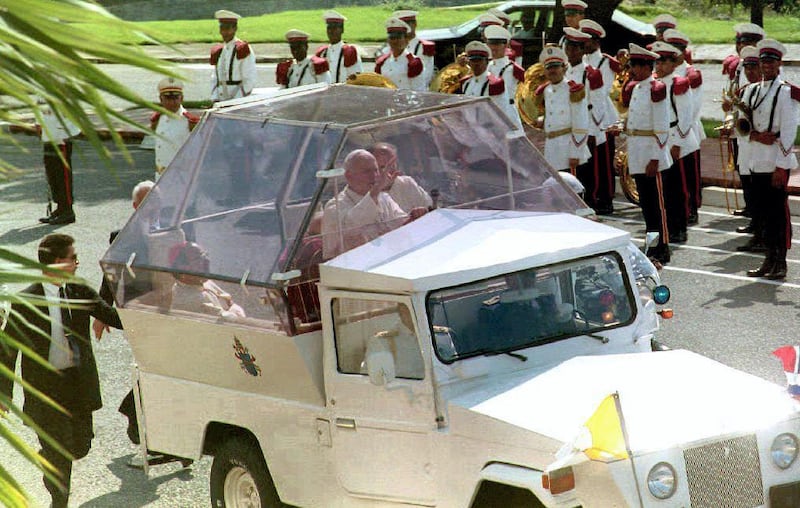 Pope John Paul II waves to people gathered outside the gates of the Presidential Palace in Santo Domingo 10 October, 1992 as he arrives to meet with President Joaquin Balaguer. The Pope, who is on his third visit to the Dominican Republic, is scheduled to inaugurate the IV Latin American cardinals and bishops conference 12 Oct. (Photo by MICHEL GANGNE / AFP)