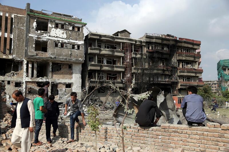 Afghan civilians watch damaged buildings in the aftermath of Sunday's attack in Kabul, Afghanistan. A complex attack against the office of the president's running mate and a former chief of intelligence service Amrullah Saleh on Sunday in the capital Kabul, killed scores of people, an official said on Monday.  AP Photo