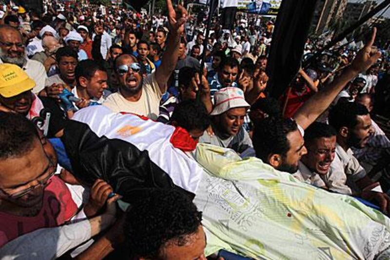 Mohammed Morsi supporters carry the body of a fellow protester killed in clashes at the Cairo headquarters of the Republican Guard. Khaled Abdullah / Reuters
