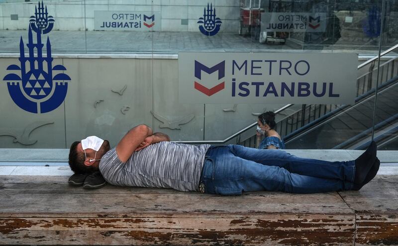 A man covers his face with face mask as he sleeps in front of the Taksim subway station, amid the ongoing coronavirus pandemic in Istanbul, Turkey.  EPA