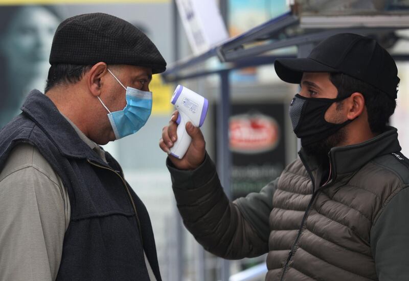 A shopper gets his temperature checked before entering a supermarket amid the COVID-19 pandemic in the Iraqi capital Baghdad on December 18, 2020. A year of economic agony for pandemic-hit and oil-reliant Iraq is drawing to a close, but a draft 2021 budget involving a hefty currency devaluation could bring more pain for citizens. Officials who prepared the document aim for "survival" solutions after an unprecedented fiscal crisis brought on by the coronavirus pandemic and the collapse in the price of oil. / AFP / AHMAD AL-RUBAYE
