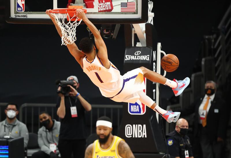 Phoenix Suns guard Devin Booker hangs from the rim after slam dunking the ball. Reuters