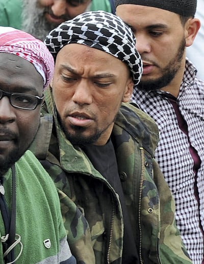 Picture taken on May 5, 2012 shows former German rapper Denis Cuspert (C) among salafi in Bonn, Germany. Denis Mamadou Cuspert, who rapped under the name Deso Dogg but took on the name Abu Talha al-Almani in Syria, was initially reported to have been killed in a suicide attack Sunday in an eastern province but hours later some retracted the claim, saying he was still alive. AFP PHOTO /DPA/  HENNING KAISER  GERMANY OUT (Photo by HENNING KAISER / DPA / AFP)