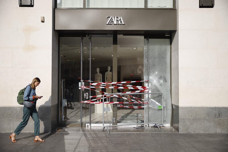 A pedestrian walks past the entrance to a damaged Zara store in Paris. AFP