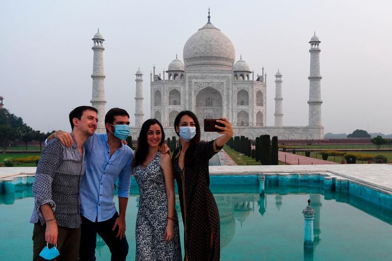 Tourists have their pictures taken at the Taj Mahal in Agra on September 21, 2020. The Taj Mahal reopens to visitors on September 21 in a symbolic business-as-usual gesture, even as India looks set to overtake the US as the global leader in coronavirus infections. / AFP / Sajjad HUSSAIN
