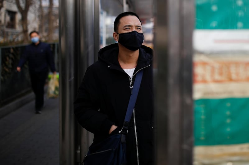 A man wearing a face mask looks at a board at a bus stop, as the country is hit by an outbreak of the new coronavirus, in Beijing, China. REUTERS