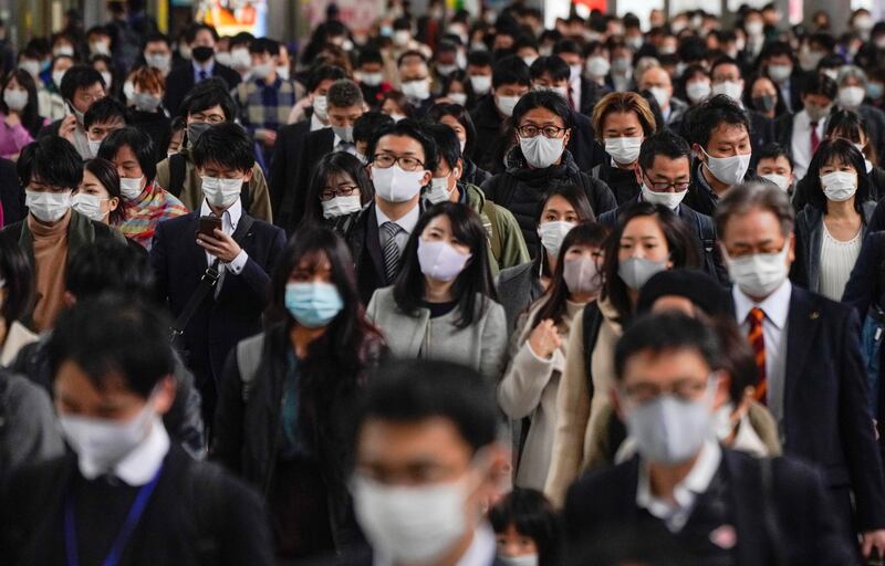 Commuters walk to work through the packed Shinagawa railway station in Tokyo on 24 November, 2020. Japan has seen a winter surge but the country of 120 million has just 300 people in intensive care. EPA