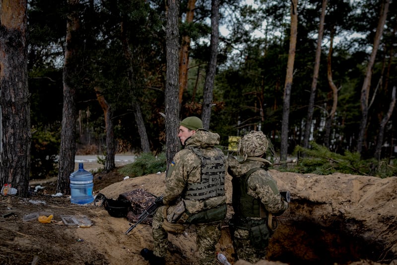 Ukrainian servicemen stand in a foxhole in Irpin. AP