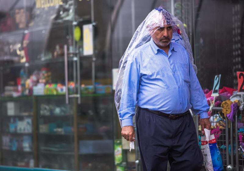 A man shields himself from the rain with a plastic bag. Victor Besa for The National