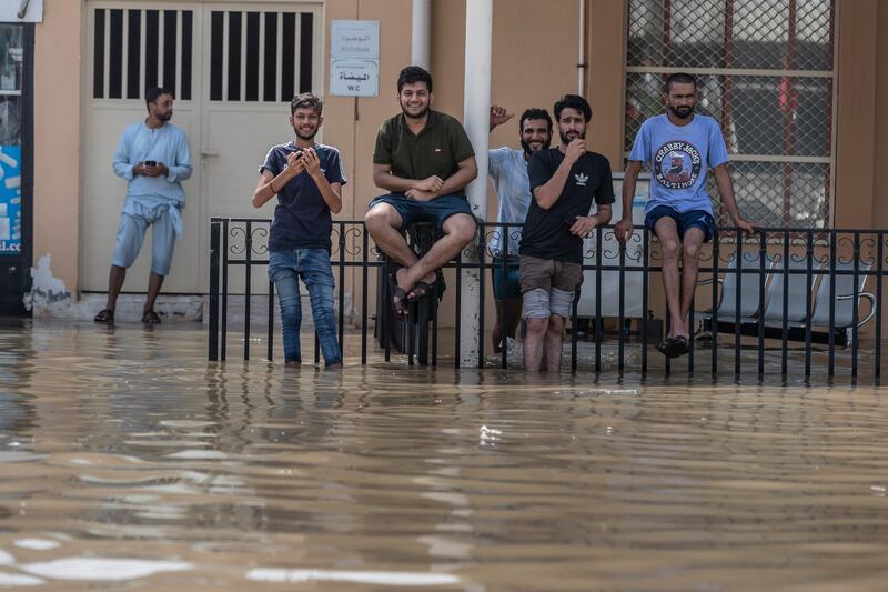 Sitting on the fence, residents are all smiles despite pools of standing water forming on roads in Fujairah city. Antonie Robertson / The National

