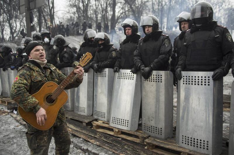 An anti-government protester plays the guitar in front of riot police at the site of clashes in Kiev on January 28, 2014. Ukrainian President Viktor Yanukovich on Tuesday accepted the resignation of prime minister Mykola Azarov and his government, said a presidential decree on his website. Konstantin Grishin / Reuters
