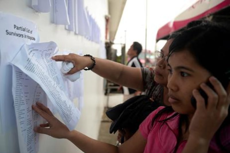 Residents look for missing relatives on a list of survivors at the company's office in Cebu City, central Philippines.  AFP Photo/Ted Aljibe