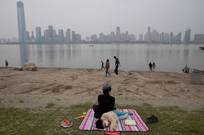 A child wearing a mask rests along the Yangtze River on April 5, 2020, in Wuhan in central China's Hubei province just days before the lifting of the cityâ€™s 76-day coronavirus lockdown. Associated Press photographer Ng Han Guan says of the photo: "Personally the photo summed up my feelings being in the city which was unceremoniously shut down and residents forced into a comatose state of inactivity that somehow became normalized.â€ Though the riverbank scene is Idyllic, he says, â€œin the background a slumbering city skyline is ready to hum back to life.â€ (AP Photo/Ng Han Guan)