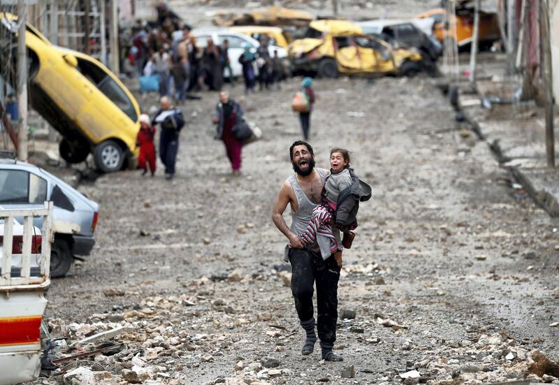 A man cries as he carries his daughter while walking from an Islamic State controlled part of Mosul towards Iraqi special forces soldiers during a battle in Mosul, Iraq, March 4, 2017. Picture taken March 4, 2017. REUTERS/Goran Tomasevic/File Photo   SEARCH "POY DECADE" FOR THIS STORY. SEARCH "REUTERS POY" FOR ALL BEST OF 2019 PACKAGES. TPX IMAGES OF THE DAY.