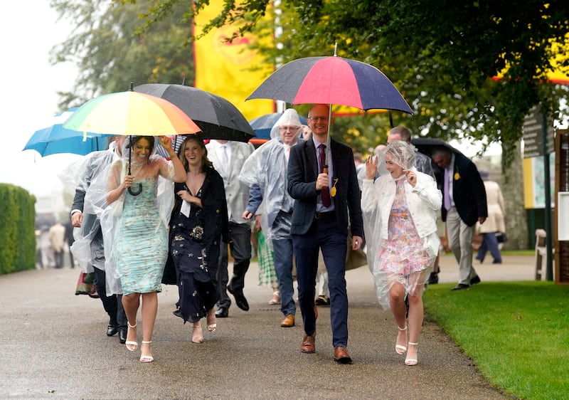 Racegoers accessorise with umbrellas and rain capes on day two of 'Glorious Goodwood' in West Sussex