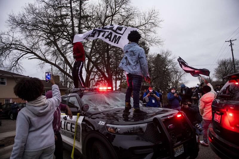 People stand on a police vehicle as protesters take to the streets after Brooklyn Center police allegedly shot and killed Daunte Wright during a traffic stop in Brooklyn Centre, Minnesota. AFP