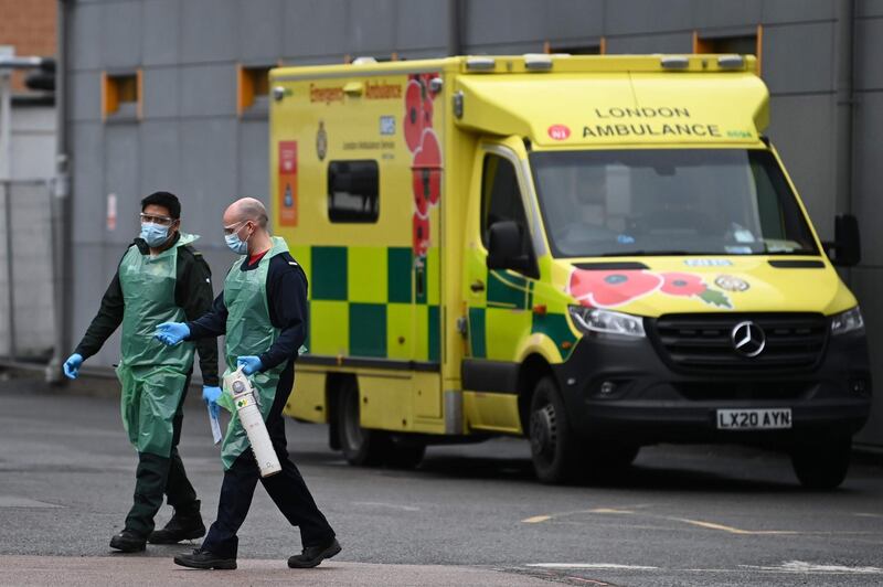 Medics carry an oxygen cannister in the ambulance park outside Lewisham Hospital in south London on January 3, 2021. The British prime minister said on January 3 he was "reconciled" to the prospect of tougher restrictions to combat spiralling coronavirus cases. Health Services are under increasing pressure after record levels of daily lab-confirmed cases of Covid-19 has led to more patients being treated in hospital in England than during the initial peak of the outbreak in April. / AFP / DANIEL LEAL-OLIVAS
