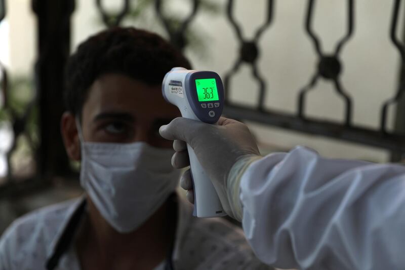 A medic checks the body temprature of a patient at a treatment centre in Ariha city, south Idlib, Syria, on August 25, 2020. EPA