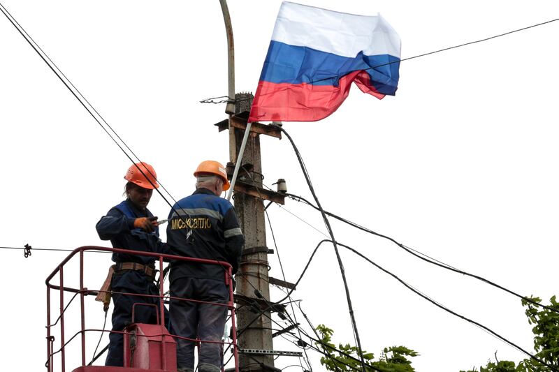 Municipal workers attach a Russian national flag to a pole in Mariupol, in territory under the government of the Donetsk People's Republic, eastern Ukraine, earlier in May. AP Photo