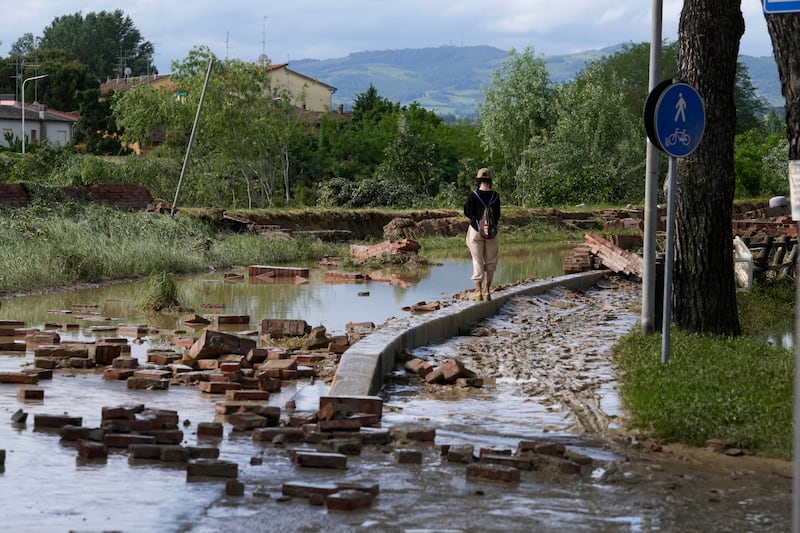 Claudia, a Faenza resident, surveys a road flooded when the  Lamone river burst its banks. AP