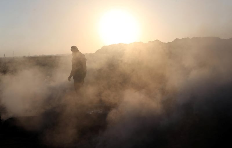 A Palestinian demonstrator is seen as smoke rises from a fire caused by objects dropped from Israeli drones during a protest against the US embassy move to Jerusalem and ahead of the 70th anniversary of Nakba, in Khan Younis in the southern Gaza Strip. Ibraheem Abu Mustafa / Reuters