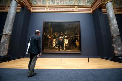 (FILES) In this file photo taken on April 4, 2013, a visitor admires Rembrandt's masterpiece "The Night Watch" in Amsterdam's Rijksmuseum, home to the world's finest collection of Golden Age art. Amsterdam's famed Rijksmuseum will on July 8, 2019 begin the biggest ever restoration of Rembrandt's "The Night Watch", erecting a huge glass cage around the painting so the public can see the work carried out live. Dubbed "Operation Night Watch", the project is the "largest and most comprehensive research on Rembrandt's masterpiece in history", the museum said in a statement. / AFP / Charles ONIANS
