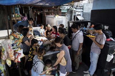 Relatives eat lunch as they visit the graves of their loved ones at a cemetery in Manila on November 1, 2018. - Millions packed cemeteries across the Catholic Philippines on November 1 to pay their respects to the dead, on a day that mixes somber reflection with the nation's penchant for festivity. (Photo by Noel CELIS / AFP)