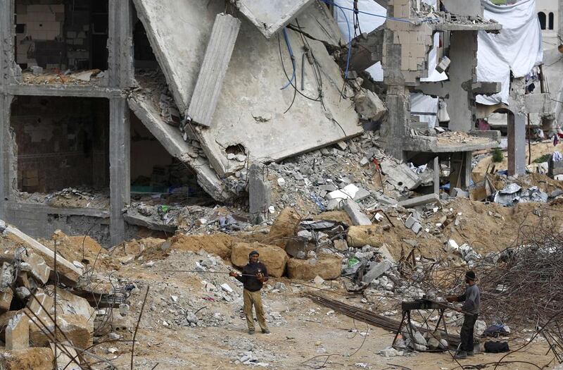 Palestinian men work next to buildings destroyed during last year’s 50-day war between Israel and Hamas-led militants, in Gaza City’s al-Shejaiya neighbourhood. Mohammed Abed / AFP 



