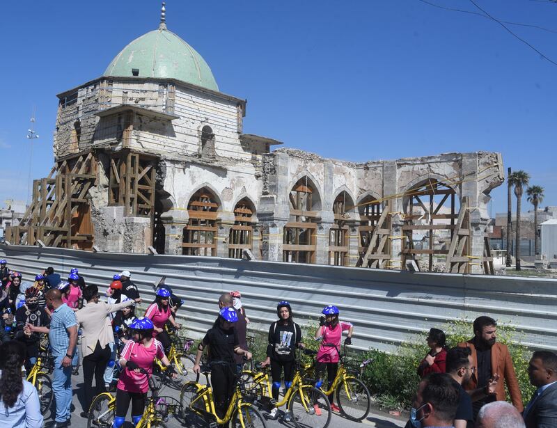 The war-damaged Great Mosque of Al Nuri, behind Iraqi female cyclists waiting to start their race. The old parts of the city were the scene of fierce fighting to drive out ISIS in 2017. EPA