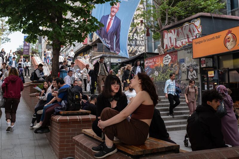 People sit on a bench by posters showing Mr Kilicdaroglu in Ankara. Getty 