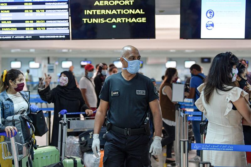 A mask-clad member of Tunisia's Rapid Intervention Brigade walks past passengers queuing to check-in their luggage before boarding departing flights at Tunis-Carthage International Airport in the Tunisian capital. AFP