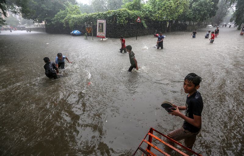 Children wade through a flooded street in Mumbai, India, July 5, 2022. EPA