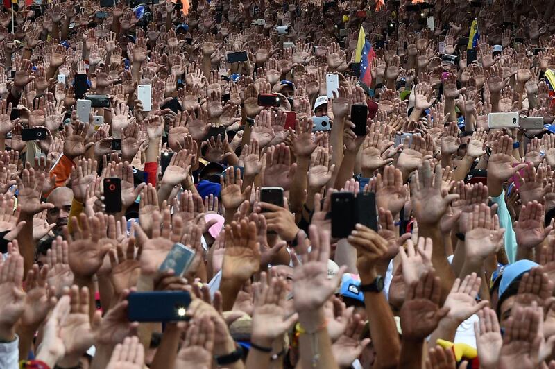 People raise their hands during a mass opposition rally against President Nicolas Maduro in Caracas, Venezuela. AFP