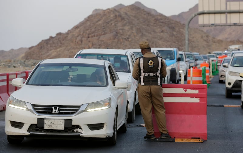 A Saudi policeman checks vehicles at at an entrance gate in Makkah. For a second straight year Hajj has been curtailed because of the coronavirus, with only vaccinated people in Saudi Arabia able to perform.