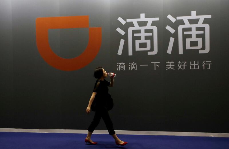 FILE PHOTO: A woman walks past ride-hailing company Didi Chuxing's booth at the Global Mobile Internet Conference (GMIC) 2017 in Beijing, China April 28, 2017. REUTERS/Jason Lee/File Photo